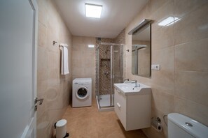 A compact bathroom with a washing machine, a sink, and a toilet. - Côte Verte (Punta Mujeres)