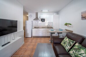 A compact living space with a kitchenette, a dining area, and a seating area with a sofa and a coffee table.