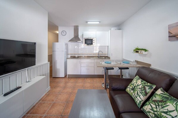 A compact living space with a kitchenette, a dining area, and a seating area with a sofa and a coffee table. - Côte Verte (Punta Mujeres)