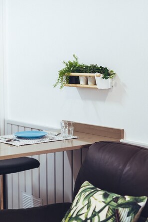 A dining area with a wooden table, a blue plate, a glass, and a black leather chair. - Green Coast (Punta Mujeres)