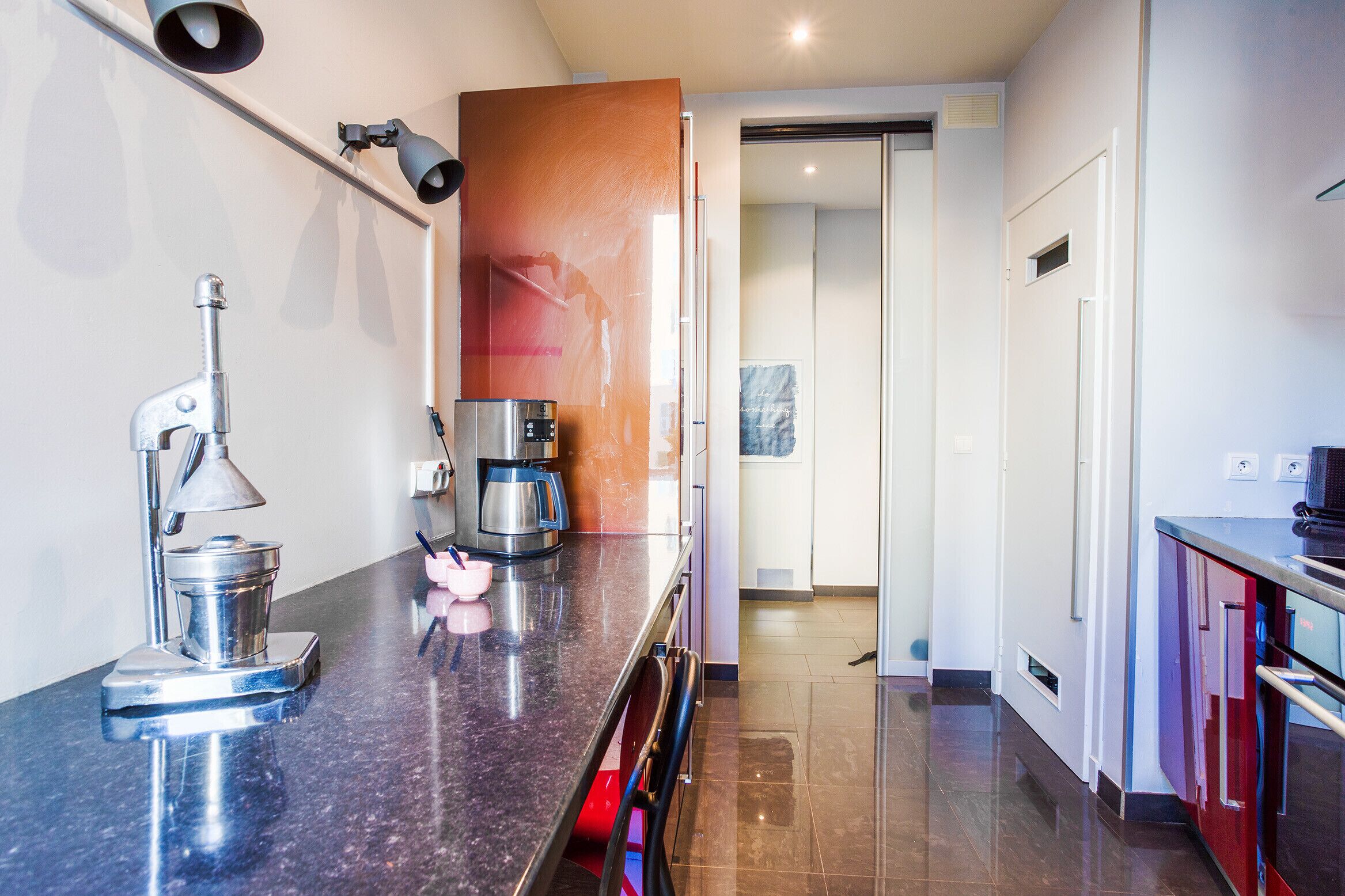 A modern kitchen with a stainless steel coffee maker, a kettle, and a coffee pot on the counter.