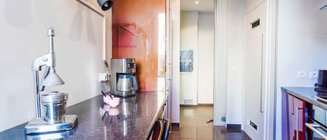 A modern kitchen with a stainless steel coffee maker, a kettle, and a coffee pot on the counter.