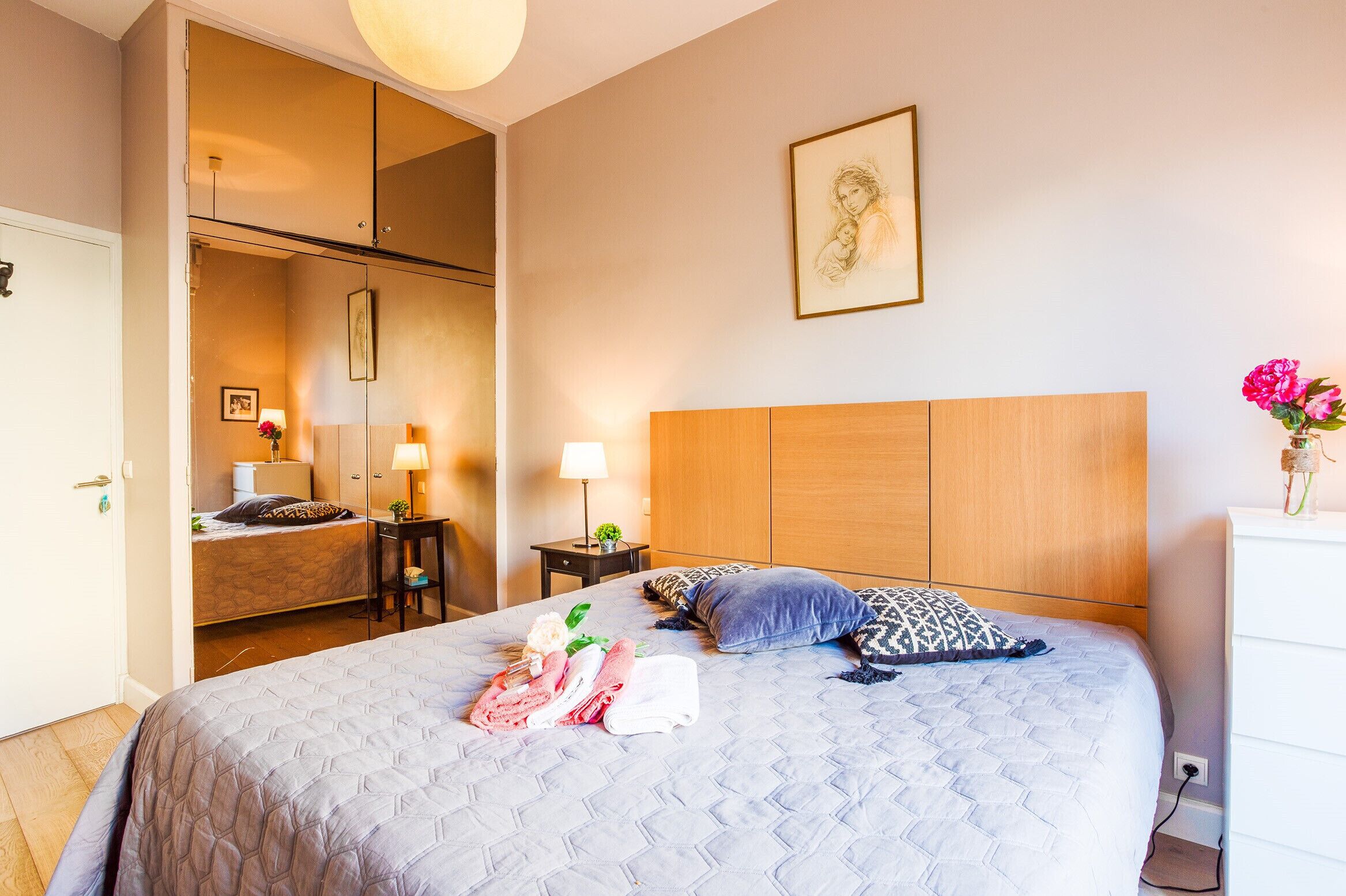 Ein Hotelzimmer mit einem großen Bett, einem Kleiderschrank, einem Nachttisch mit Lampe und einem Bild an der Wand.