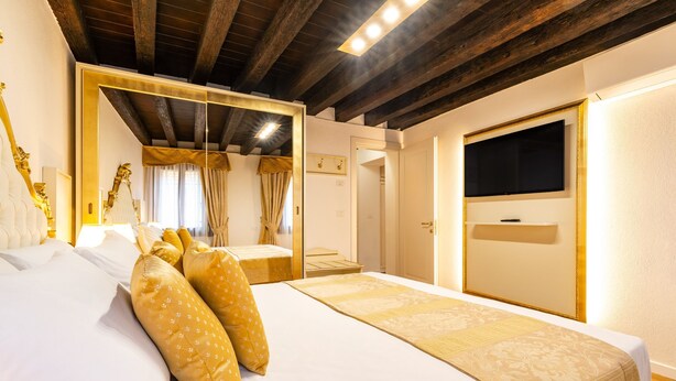 Une chambre d’hôtel avec un grand lit, une télévision et un plafond en bois.