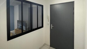 Ein Flur mit einem großen Spiegel, einer dunklen Tür und einem Fliesenboden.