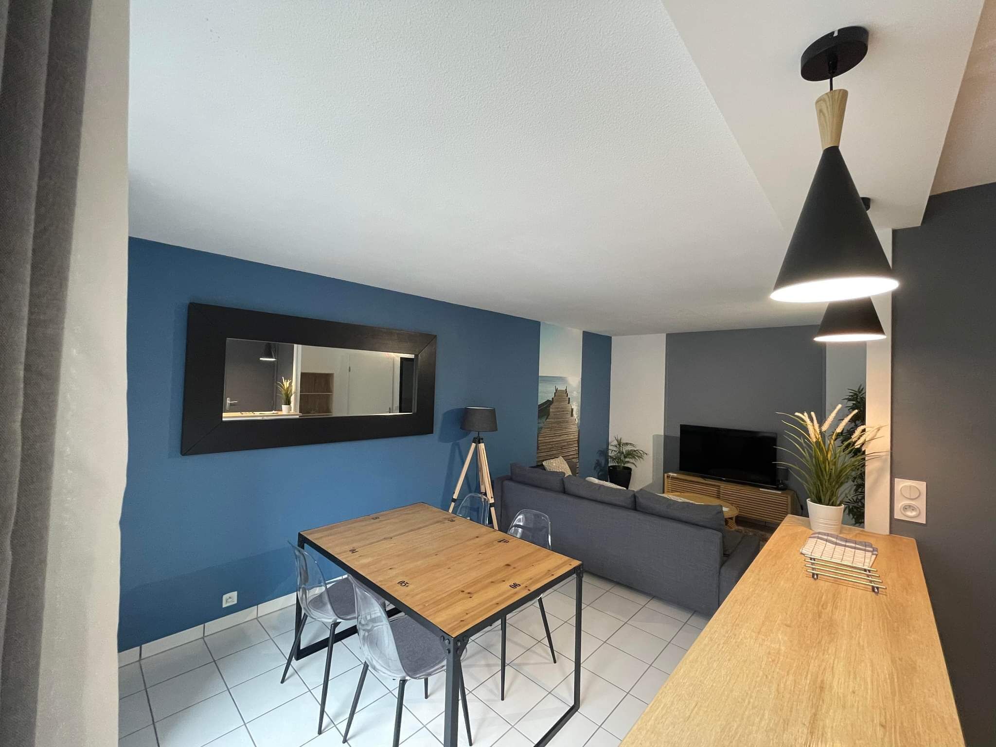 Ein modernes Wohnzimmer mit Holzesstisch, einer Couch und einem Fernseher.