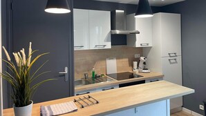 Eine moderne Küche mit dunklen Schränken, einer Holz Arbeitsplatte und Pendelleuchten.