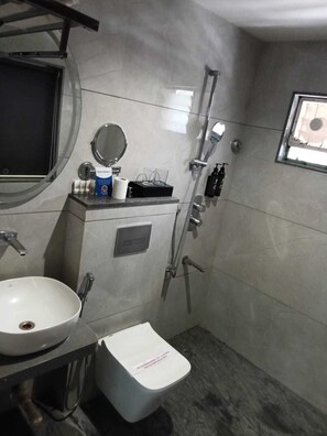 A bathroom with a white sink, mirror, toilet, and shower.