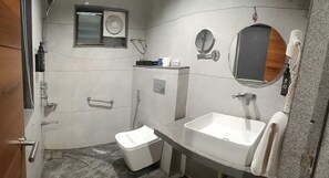 A bathroom with a toilet, sink, mirror, and shower. - RG Exclusive Stay & Fine Dine, Akola (Akola)