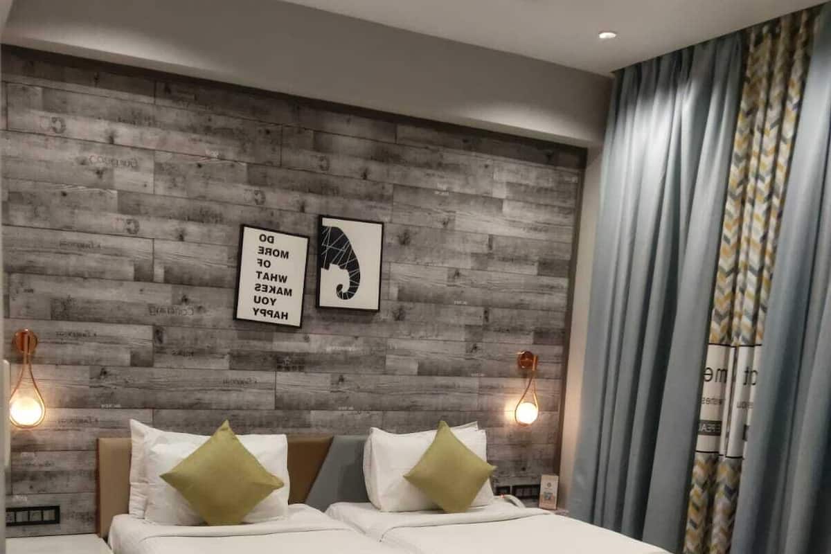 A modern bedroom with a wooden headboard, two bedside tables, a bed with white bedding and green pillows, and a wall with two framed pictures.