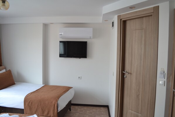 Une chambre d’hôtel équipée d’un lit, d’un téléviseur fixé au mur, d’un appareil de climatisation et d’une porte en bois.