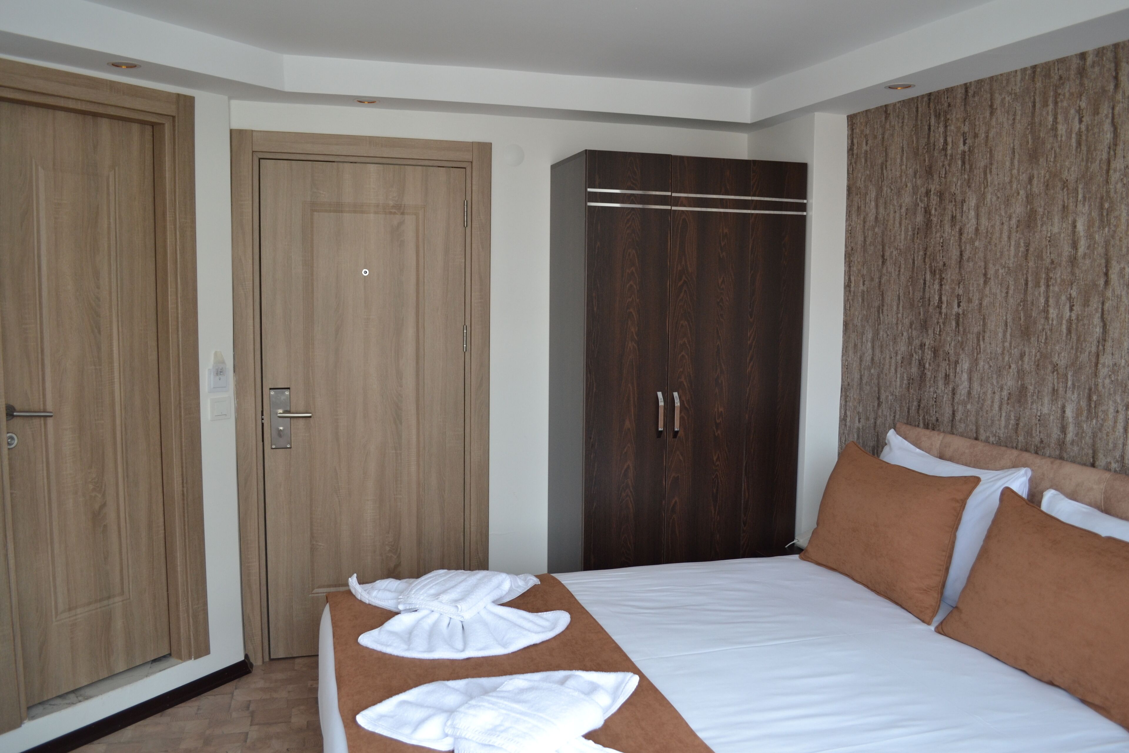 Una habitación de hotel con una cama, un armario de madera y un vestidor amplio con espejo.