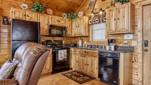 Een keuken in chaletstijl met houten kastjes, een koelkast, fornuis, magnetron en vaatwasser.