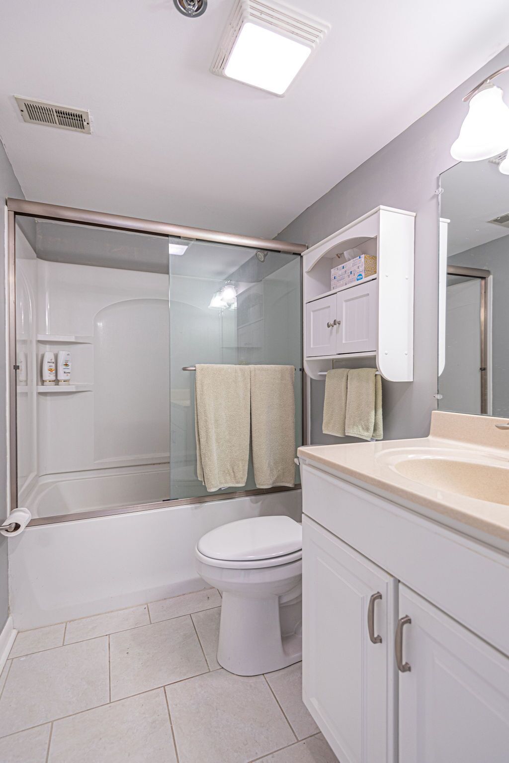 A bathroom with a shower enclosure, a toilet, and a sink with a mirror.