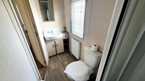 Et lille badeværelse med vask, toilet og spejl.