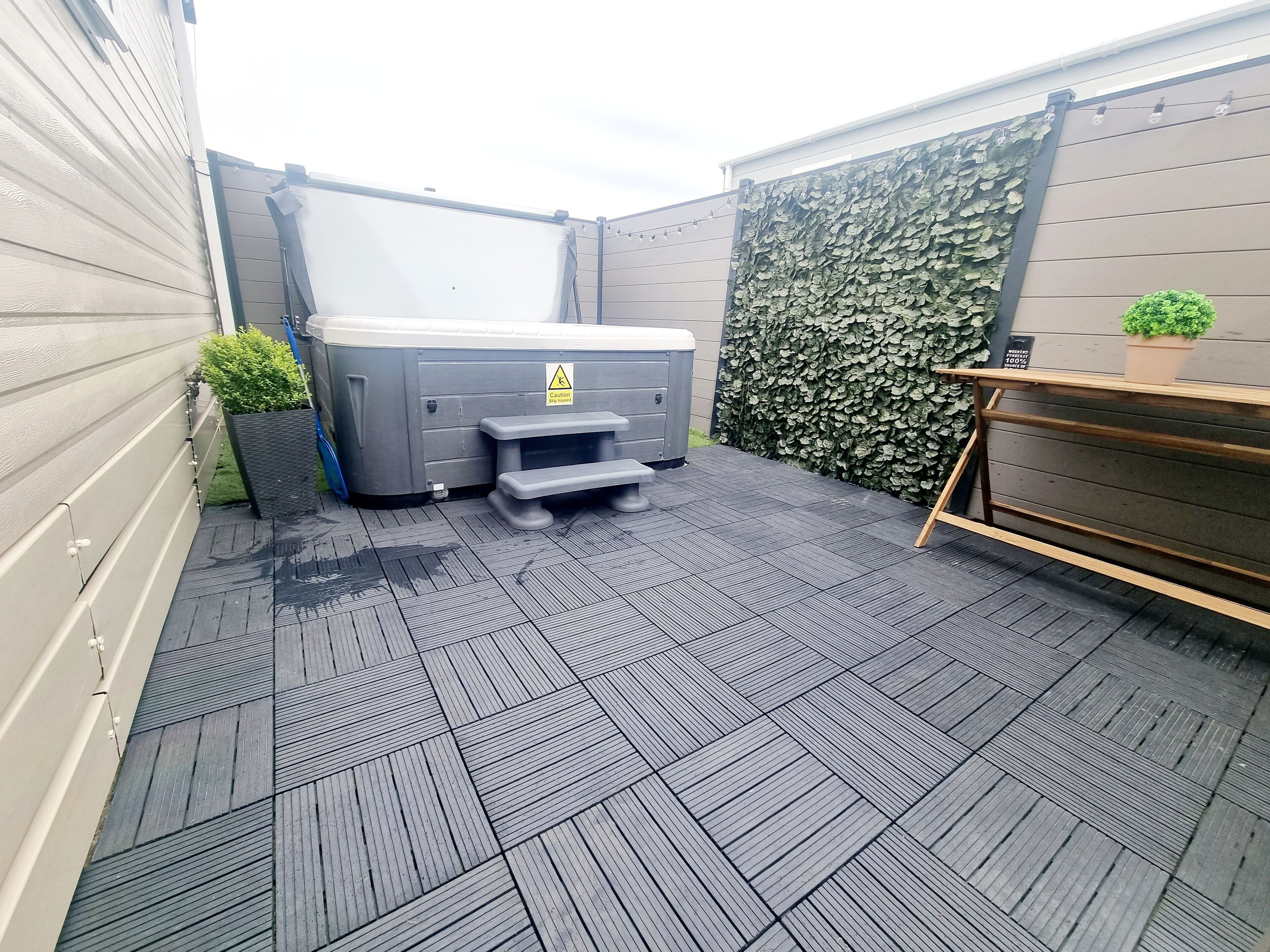 Un espace extérieur aménagé, de taille réduite, comprenant un jacuzzi, un banc et un pot de fleurs.