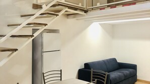 A modern interior with a dining area, a sofa, and a staircase leading to an upper level. - B&B in the wonderful and evocative center of Rodi Garganico (Rodi Garganico)