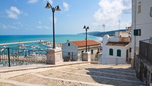 A coastal town with a marina, stone steps leading to buildings with red-tiled roofs, and a clear blue sky. - B&B in the wonderful and evocative center of Rodi Garganico (Rodi Garganico)