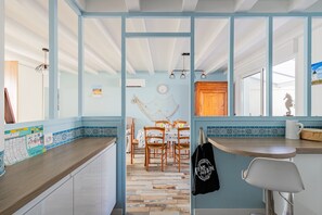 Una cocina con encimera de madera, un comedor con sillas y un reloj fijado a la pared.
