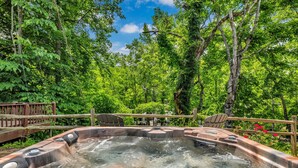 A hot tub surrounded by lush greenery and a wooden deck with chairs. - Riverfront, ½ Mile to Smoky Mtn National Park (Townsend)