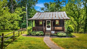 A rustic cabin with a metal roof, a wooden porch, and a stone pathway leading to the entrance. - Riverfront, ½ Mile to Smoky Mtn National Park (Townsend)