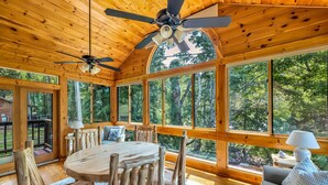 A wooden cabin with a dining table and chairs, large windows, and a ceiling fan. - Riverfront, ½ Mile to Smoky Mtn National Park (Townsend)