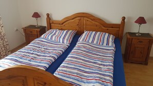 A double bed with a striped bedspread, two nightstands with lamps, and a wooden headboard. - House (Dornum)