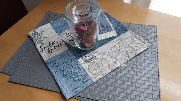 A glass jar with a label on a table with a placemat that has text and a pattern. - House (Dornum)