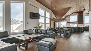 A spacious living area with a wooden ceiling, large windows, a dining area, and a kitchen. - Domaine Des Mésanges (Beaupré)