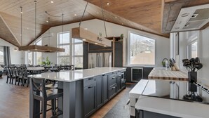 A spacious kitchen with a large island, dark cabinetry, and a wooden ceiling. - Domaine Des Mésanges (Beaupré)