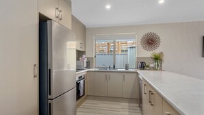 Een moderne keuken met roestvrijstalen apparatuur, een groot raam en een decoratief kunstwerk.