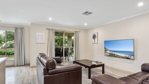 Een moderne woonkamer met een leren bank, een salontafel en een groot schilderij met uitzicht op het strand.
