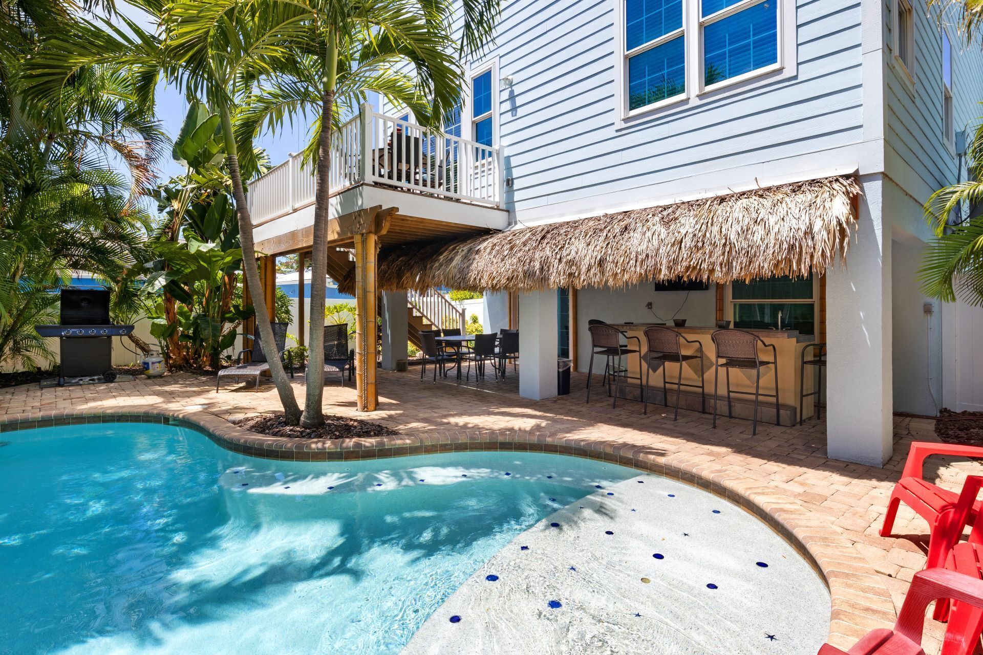 A pool area with a hot tub, outdoor seating, and a barbecue grill.