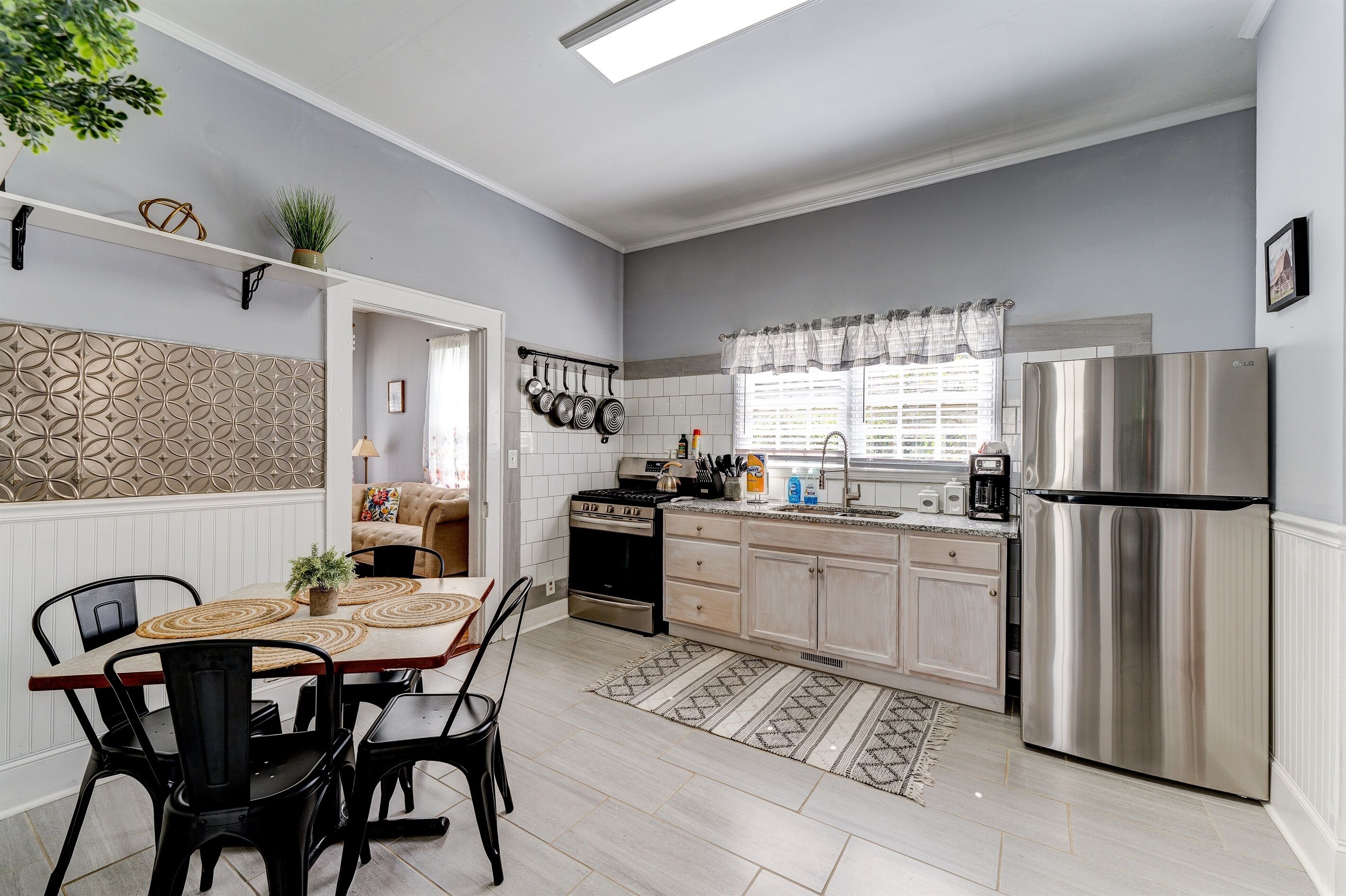 Una cocina moderna con comedor, que incluye un refrigerador de acero inoxidable, una estufa y una mesa de comedor con sillas.