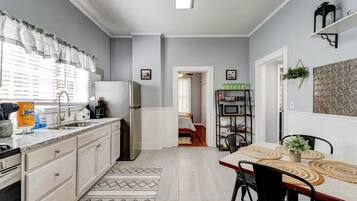 A modern kitchen with a granite countertop, white cabinets, and a dining area with a wooden table and chairs.