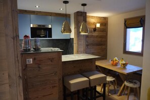 A kitchen with wooden accents, a bar area, and a window with curtains.