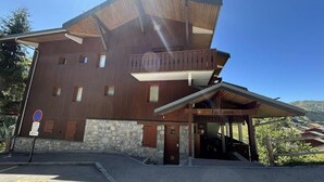 A two-story wooden building with a stone base, a covered entrance, and a sign indicating 'Le Lama'. - 230m from ski slopes, floor -3, view mountain, balcony, 44m², Méribel-Mottaret (Méribel - Les Allues)