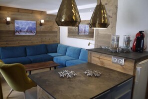 A modern kitchen with a wooden countertop, a blue sofa, and a yellow chair.