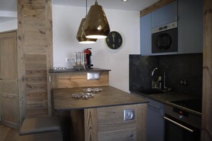 A kitchen with a wooden island, a clock, and a coffee machine.