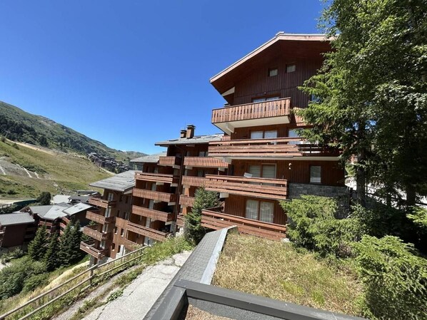 A multi-story wooden building with balconies, set in a mountainous area.