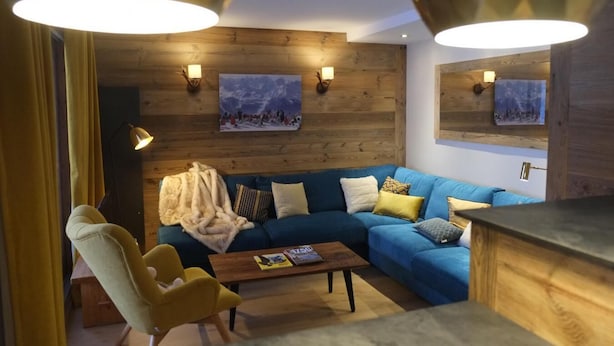 A cozy living room with a blue sofa, yellow armchair, and wooden accents. - 230m from ski slopes, floor -3, view mountain, balcony, 44m², Méribel-Mottaret (Méribel - Les Allues)