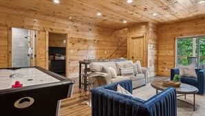 Ein gemütliches Blockhaus-Interieur mit Billardtisch, einer Couch und einem Couchtisch.