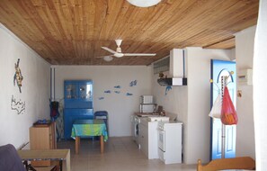 Un espace de vie compact comprenant un coin cuisine, un coin repas et une chambre.
