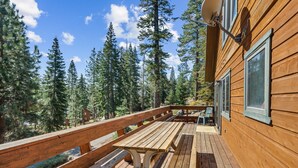 Eine Holzterrasse mit Picknicktischen, mit Blick auf eine bewaldete Gegend.