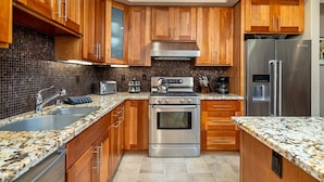 A modern kitchen with wooden cabinets, a stainless steel oven, and a refrigerator. - Modern Condo- Jacuzzi Tub SM #201 by Bear Valley Vacation Rentals (Arnold)