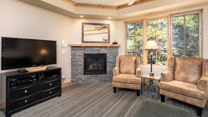 A living room with a fireplace, a television, and two armchairs.