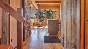 A wooden interior with a staircase, stone wall, and a view of the outdoors. - Overlooking Beautiful Bear Lake VH#318 by Bear Valley Vacation Rentals (Arnold)