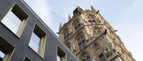 A modern building with large windows and a historic building with intricate stonework and statues in the background.