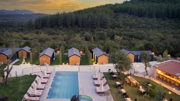 Relax by the pool surrounded by lush greenery and distant hills.
