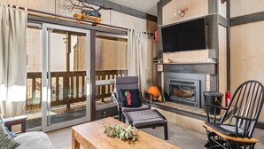 Una sala de estar acogedora con chimenea, un ventanal grande y un portón corredero que da a un espacio exterior.